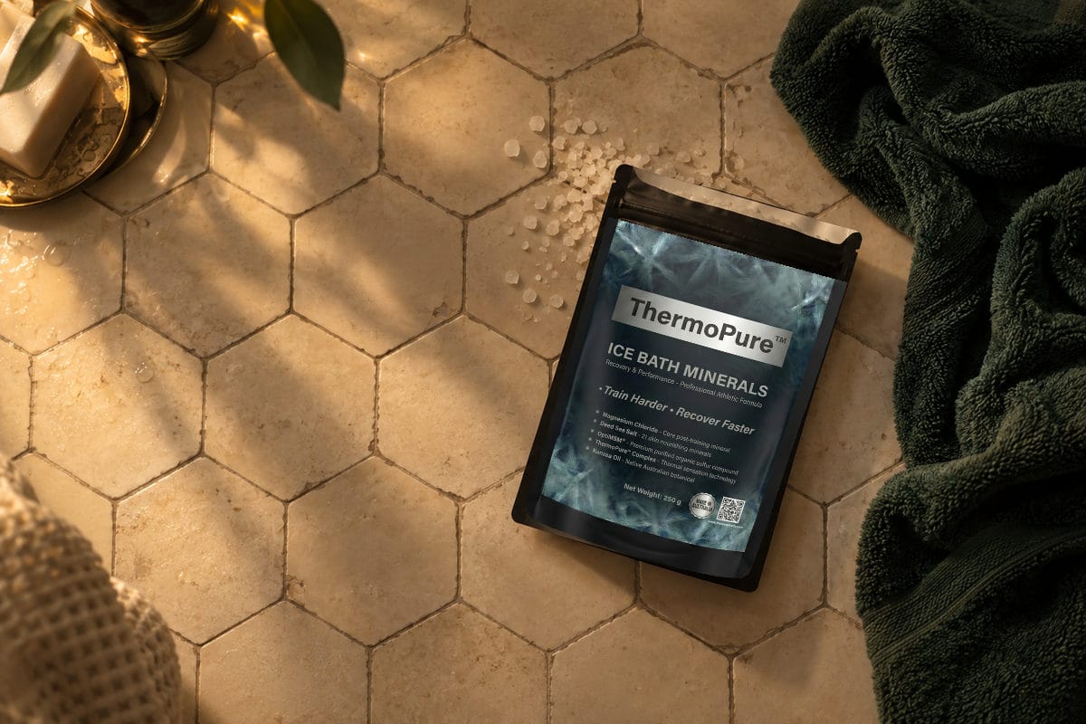 An open ThermoPure minerals pouch rests beside a green towel on warm ivory bathroom tiles.